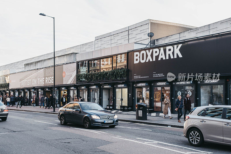 在英国伦敦的BOXPARK Shoreditch的商店前，人们和汽车。